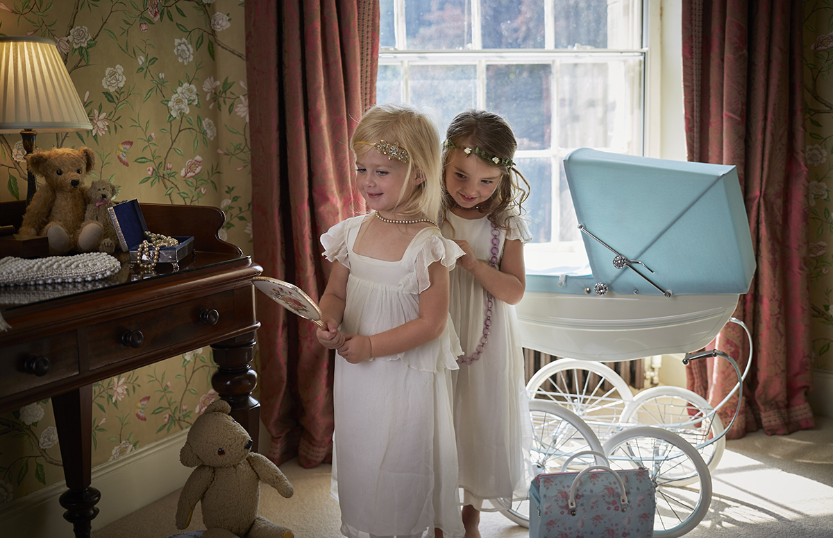 two girls dressing up next to a silver cross pram