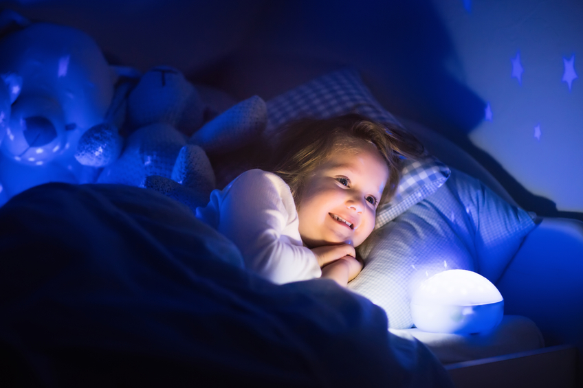 Cute little girl reading a book in bed