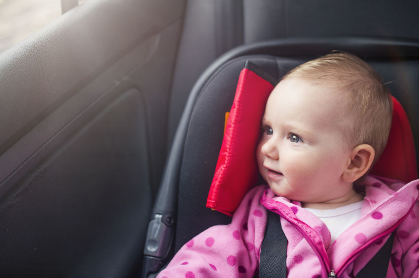 Little baby girl in a car in a child seat