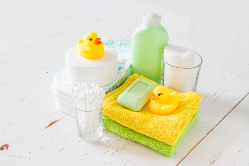 Pampering - towel, diapers, lotion, soap, cotton pads and sticks, toy ducks, white wood background