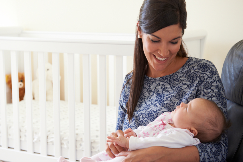 Happy Mother Sitting In Nursery With Baby