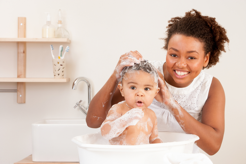 Mother smiling for the camera whilst bathing her son