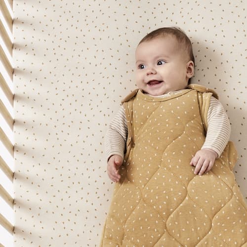 baby smiling with brown spotted dress