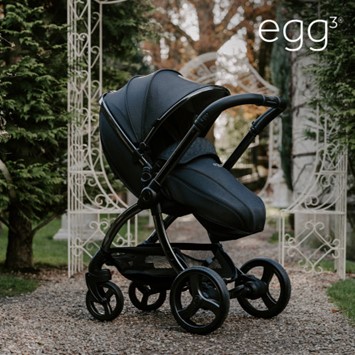 A black baby stroller in a gravel path